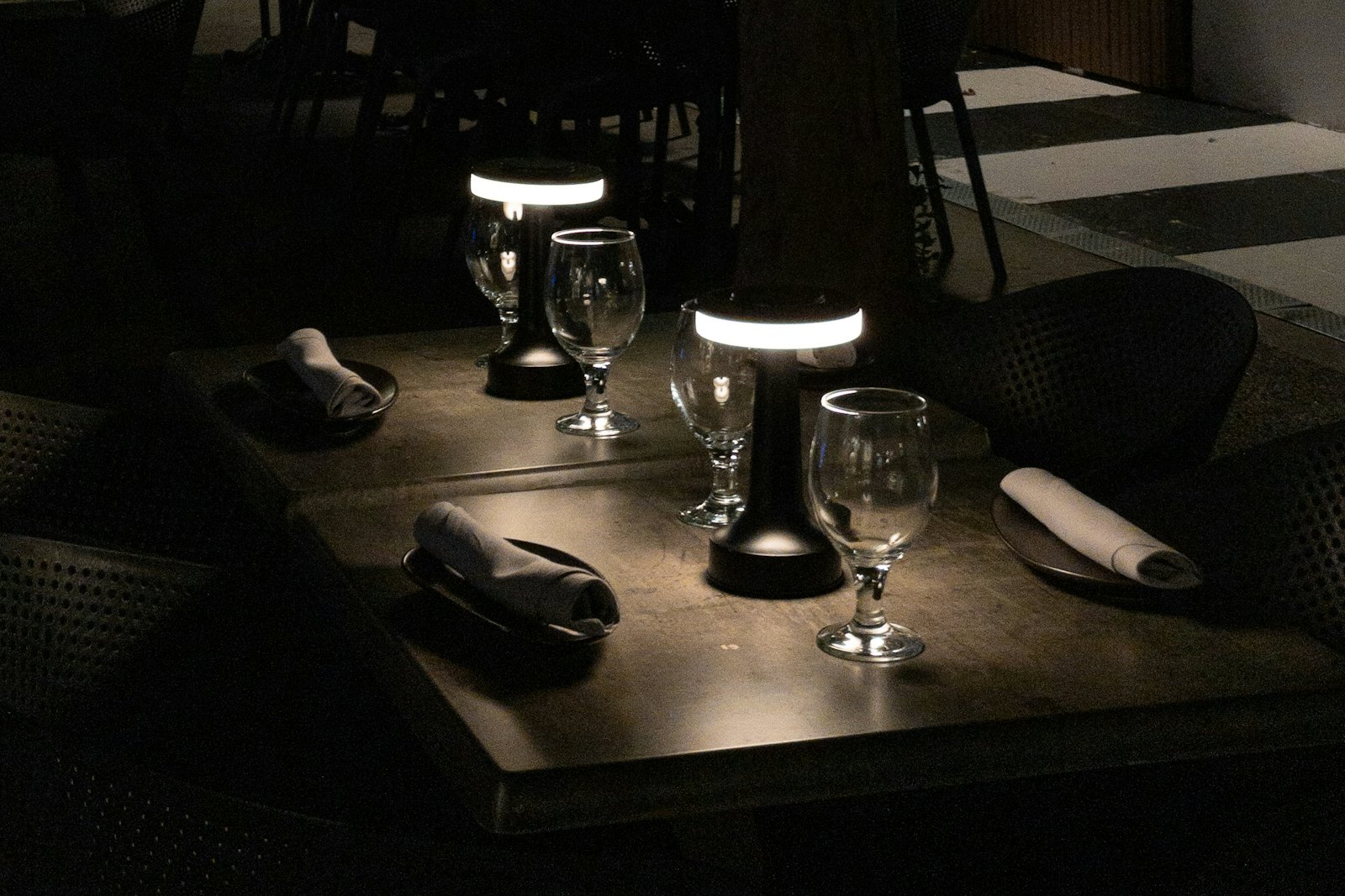 A dark restaurant table set with wine glasses under low lamps